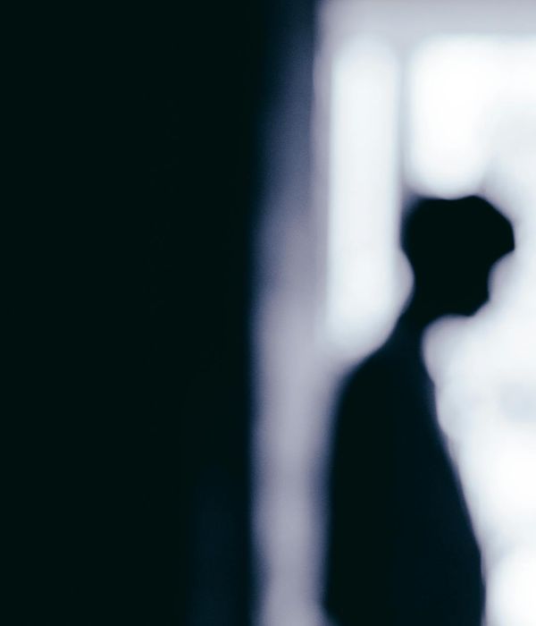 Person meditating peacefully near a window with soft light.